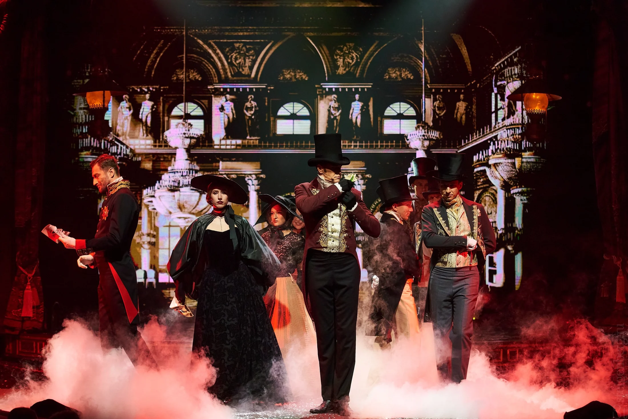 Wide theatrical ensemble scene in smoke and stage light