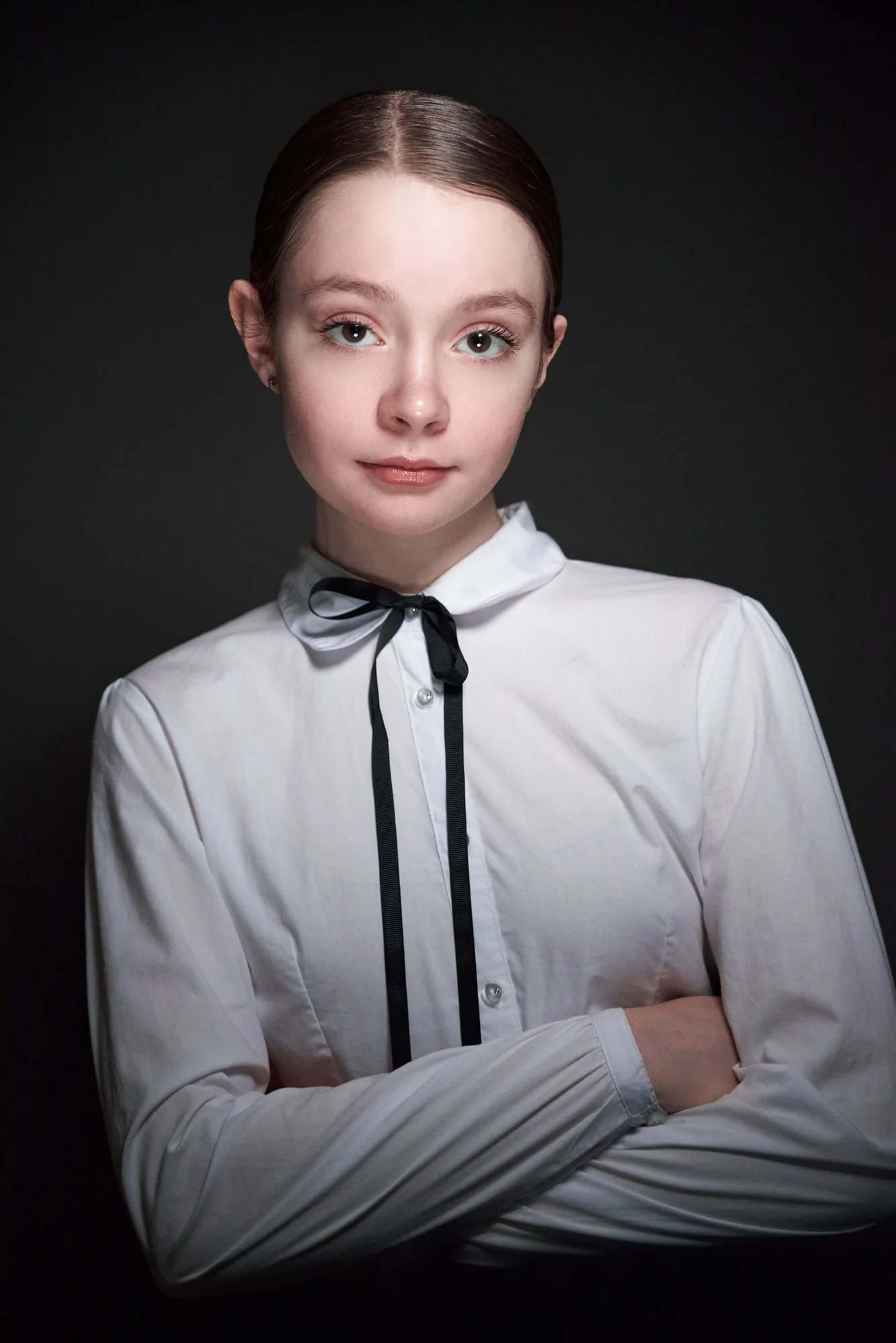 Studio portrait of a teenage girl in a white shirt and black ribbon