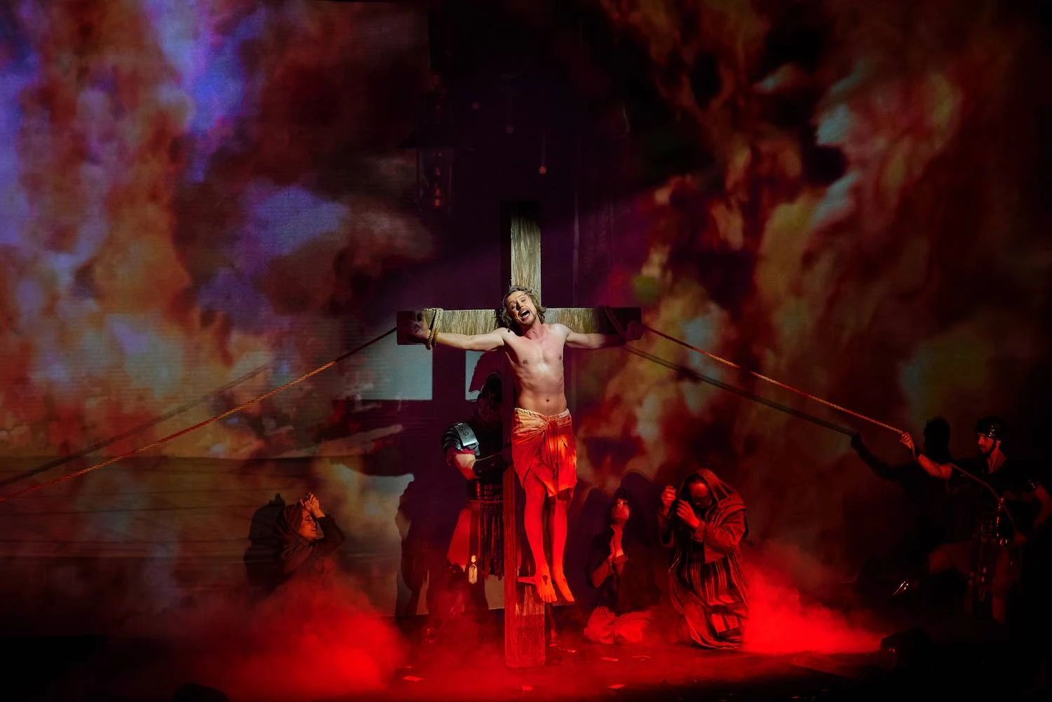 Crucifixion scene surrounded by red theatrical light and smoke