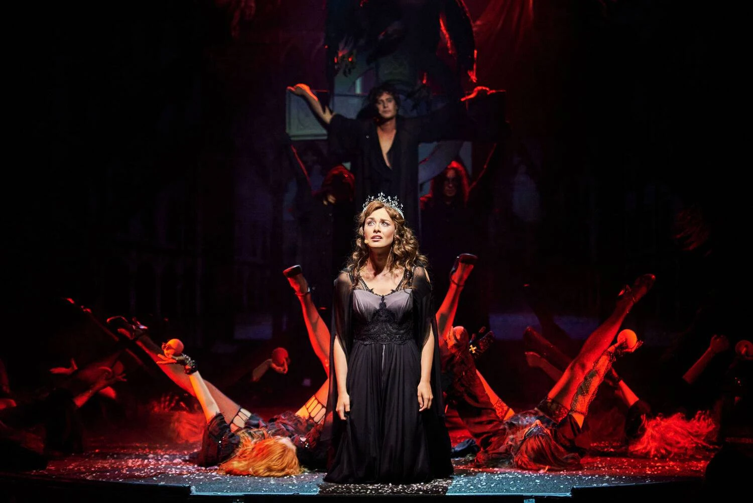 Central female performer in a dramatic red and black theatrical scene