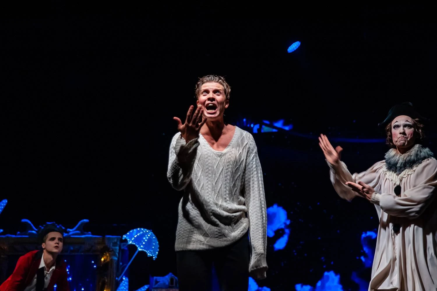 Actor in a white sweater caught in an expressive stage moment